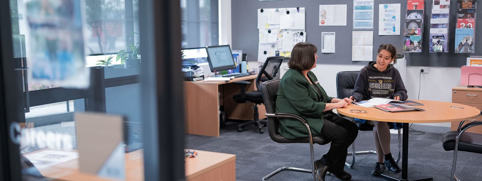 Two women sitting at a table in an office setting.